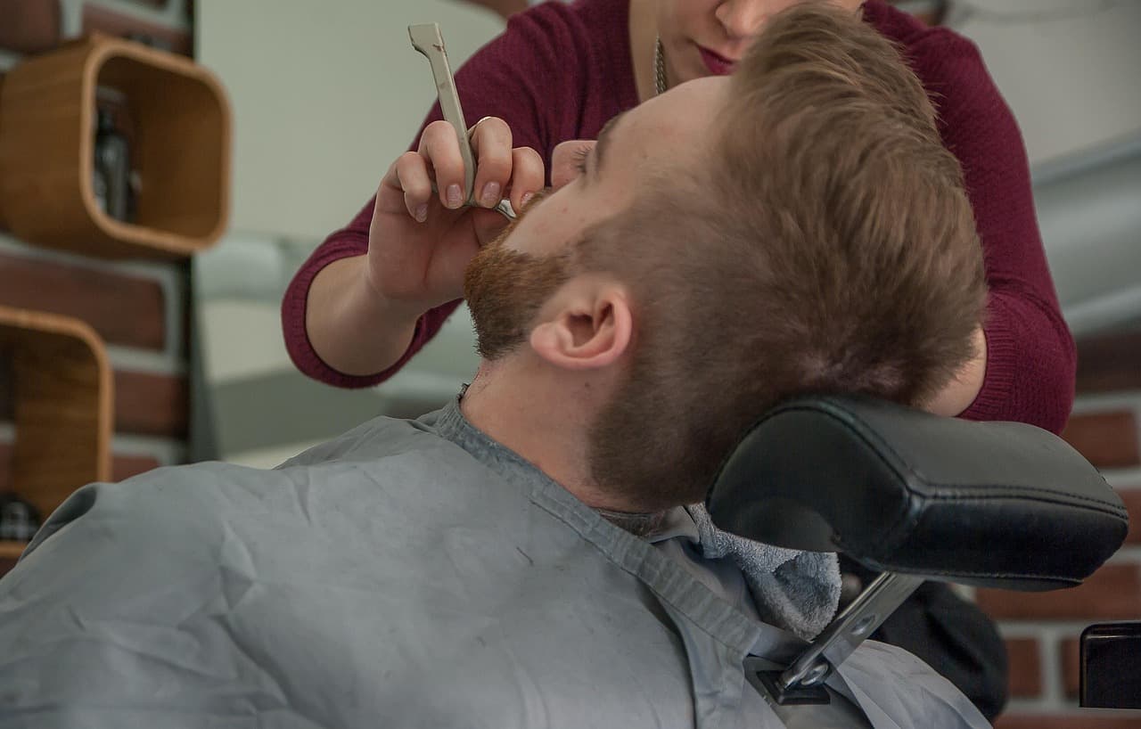 Barber shaping under a customer's beard with a straight razor