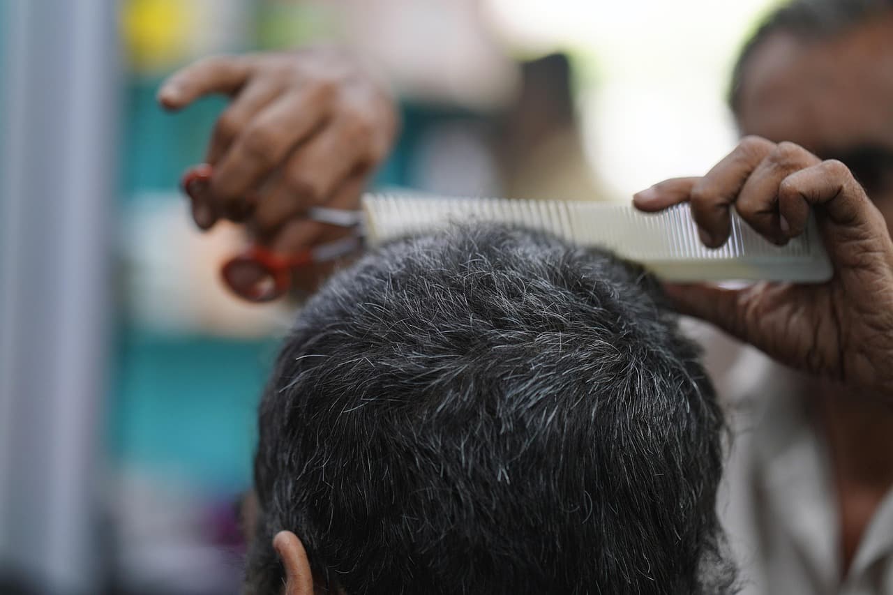 Comb and scissors working through short dark hair